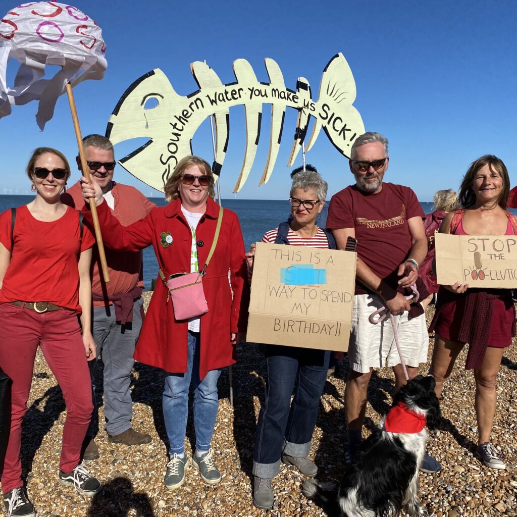 Photo of a group of people on the beach with placards protesting against water pollution