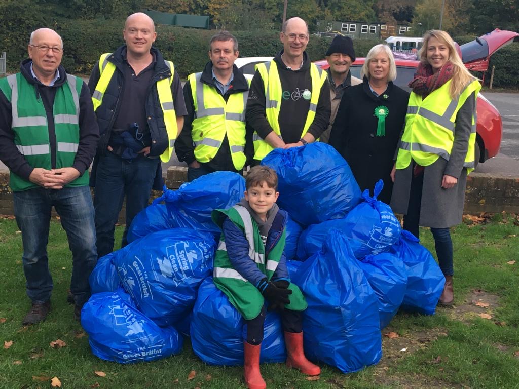 Photo of a group of people in high viz vests and a pile of dustbin bags full of rubbish