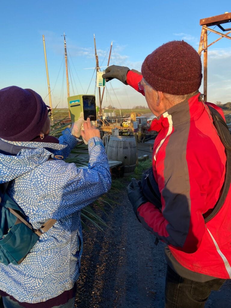 Photo of the back of two people looking at water testing results with boats in the background